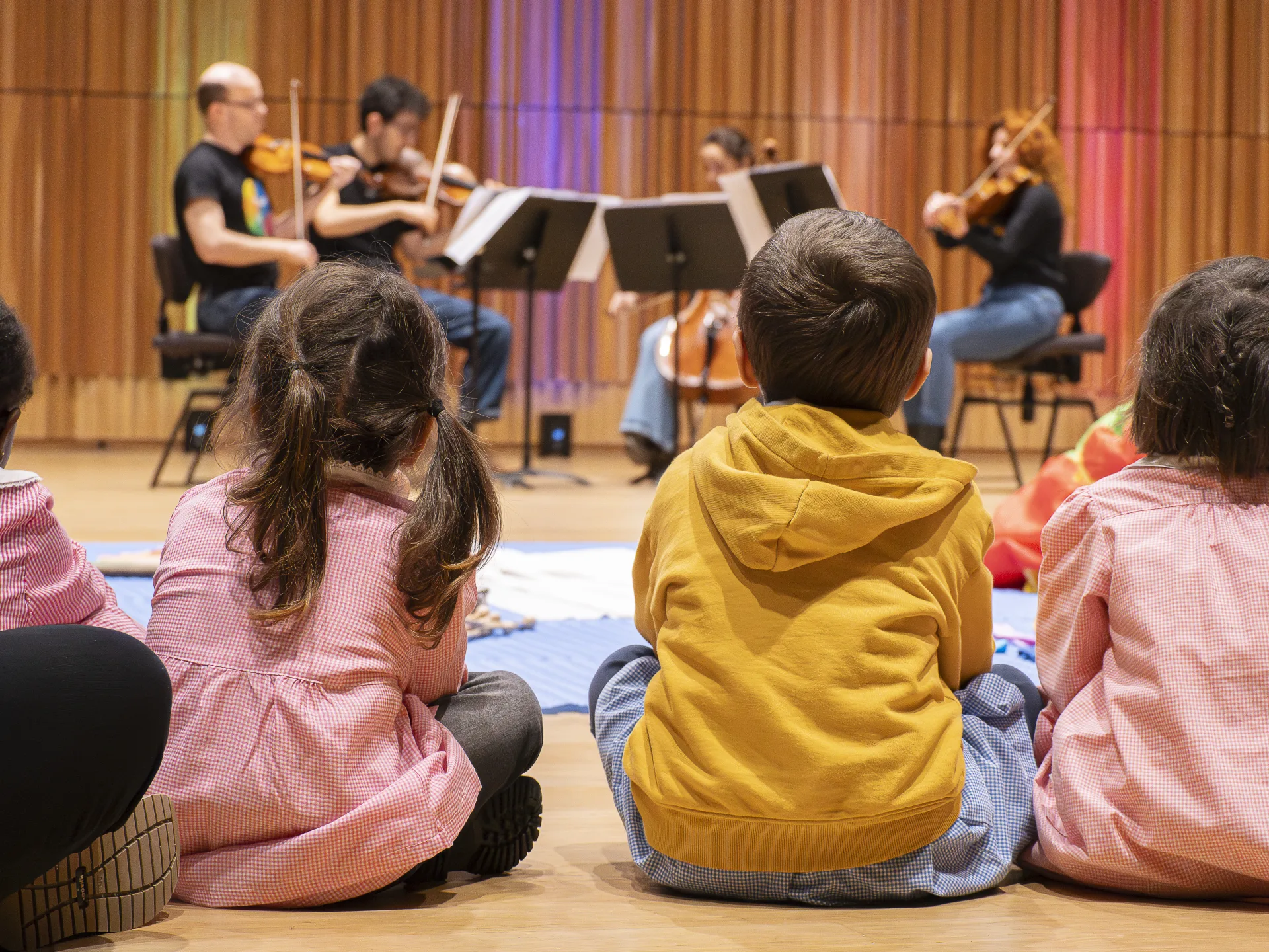Bambini e musicisti seduti in cerchio a terra durante il laboratorio interattivo Cerchi di musica